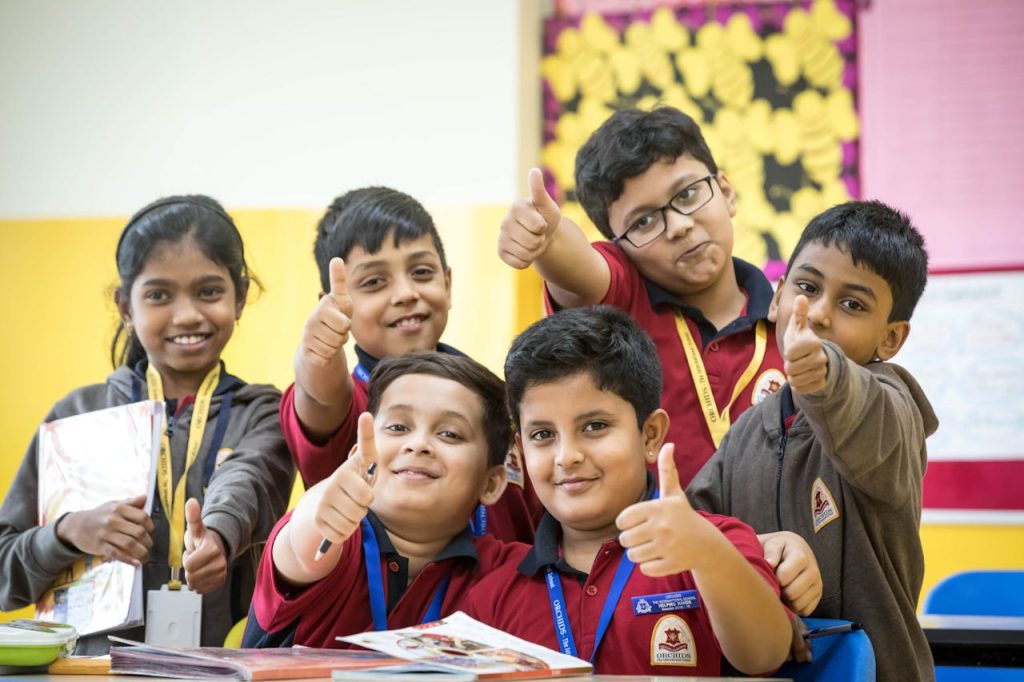 a-group-of-students-doing-a-thumbs-up-11366728 Group of cheerful school children showing thumbs up while studying together in a colorful classroom.