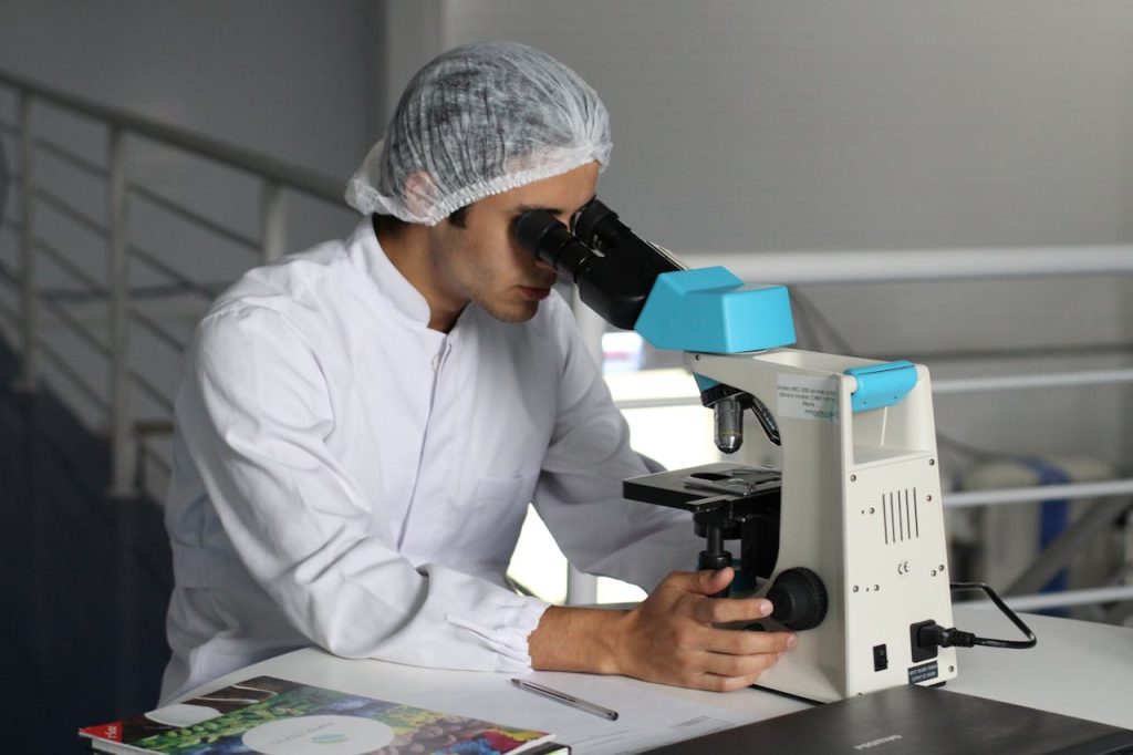 men-s-white-dress-shirt-356040 Scientist in a lab coat using a microscope to conduct research, focusing on healthcare improvements.